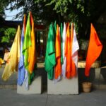 Colorful fabric flags orange green white blue yellow billow on poles in a courtyard with a person in a yellow shirt nearby Sarathi school habsiguda hyderabad