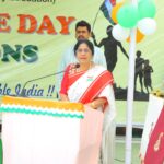 Indian woman in a red and white saree speaks at a decorated podium during a public celebration event Sarathi school habsiguda hyderabad