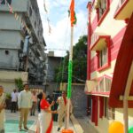People participate in a flag raising ceremony in a courtyard a tall pole wrapped in orange white and green at the center Sarathi school habsiguda hyderabad