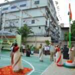 Schoolyard independence day celebration with students in uniform and teachers saluting in front of sarathi school banner on a green court Sarathi school habsiguda hyderabad