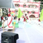 Students in white uniforms with green sashes marching in a school independence day parade on a decorated courtyard with a woman in a sari saluting from a raised platform and a pink building in the background Sarathi school habsiguda hyderabad