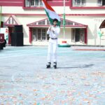 A young man on roller skates holds the indian flag during a school republic day celebration with colorful bunting overhead Sarathi school habsiguda hyderabad