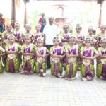 Group of young indian classical dancers in green and purple costumes posing in a courtyard with a man in a white shirt standing behind them Sarathi school habsiguda hyderabad